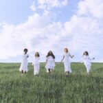 Group of People Standing on Green Grass Field Under Blue Sky