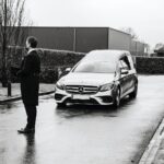 man in black jacket standing beside silver mercedes benz car