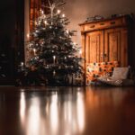 Christmas tree with turned on mini string lights near cabinet