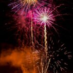 a large fireworks display with a castle in the background