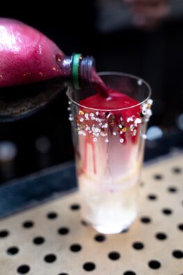 a person pouring a drink into a glass