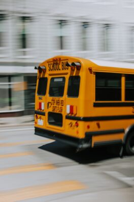 A yellow school bus is speeding through a city.