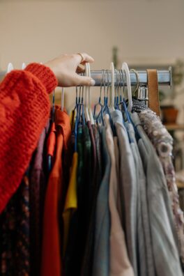 A woman browsing garments on hangers in a retail clothing store.
