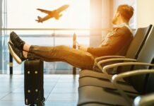 Apre lista regalo in agenzia viaggi ma spariscono 750 euro, due denunce man sitting on gang chair with feet on luggage looking at airplane