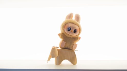 A plush toy rides a wooden animal.