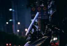Passaggio di proprietà della moto: documenti, costi e nuova assicurazione A dark scooter parked on a city street at night.
