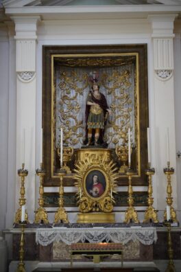 Luxurious altar in Urbino's church showcasing intricate gold designs and religious sculptures.