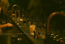 Alcol a minori e irregolarità amministrative, un commerciante denunciato e tre sanzionati A dimly lit bar with a drink and bar tools creating a moody atmosphere.