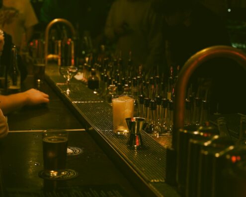 A dimly lit bar with a drink and bar tools creating a moody atmosphere.