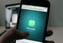 Chat WhatsApp tra colleghi: annullata la sanzione disciplinare inflitta al dipendente che attacca l’azienda nei vocali postati A smartphone displaying the WhatsApp application screen held by a person.