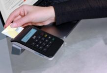 Usa carta di credito rubata per fare acquisti, denunciato Hand inserting card into contactless payment terminal for secure online transaction.