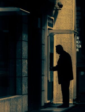 A man in silhouette using an ATM machine in an urban area of Cide, Kastamonu, Türkiye.