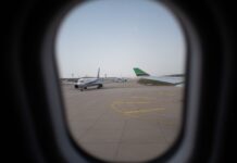 Ruba un paio di occhiali e un profumo: 55enne fermato in aereo Airplane seen through a window, parked on the airport runway, capturing a travel moment.