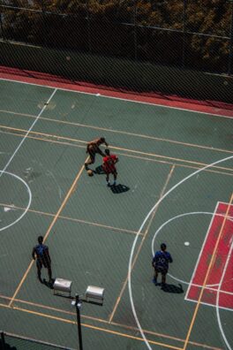 Aerial shot of four men playing basketball on an outdoor court.