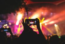 A Lampedusa nasce Alta Stagione 2026: Rocco Hunt, Andrea Damante e Merk & Kremont in dj set person holding smartphone taking video of a concert near stage with lights during nighttime